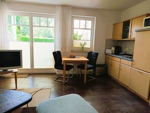 A compact living space with a dining area, kitchenette, and a TV.