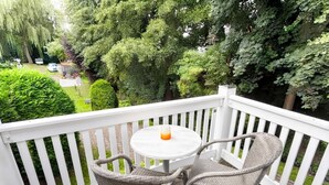 Une terrasse en bois avec une balustrade blanche, une table ronde et deux chaises en osier.