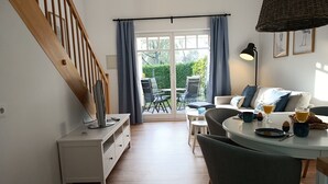 A modern living room with a staircase, a dining area, and a view of the garden through the glass door. - Apartment Rosenhof 12 - Wh. 12 (Kühlungsborn)
