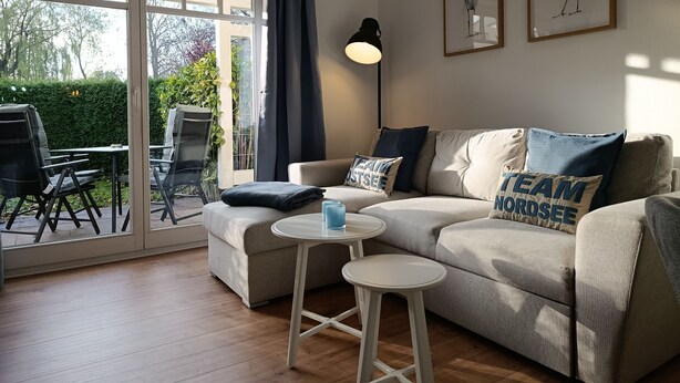 A living room with a sofa, two side tables, and a large window with curtains. - Apartment Rosenhof 12 - Wh. 12 (Kühlungsborn)