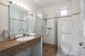 A bathroom with a granite countertop sink, a glass shower enclosure, and a toilet. - Apartment Rosenhof 11 - Wh. 11 (Kühlungsborn)