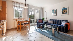 A spacious living area with a dining table, sofa, and artwork on the walls. - Apartment Rosenhof 11 - Wh. 11 (Kühlungsborn)