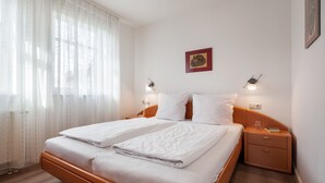 A neatly made bed with white linens, a wooden headboard, and two bedside tables with lamps. - Apartment Rosenhof 11 - Wh. 11 (Kühlungsborn)