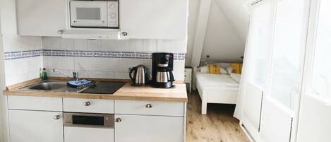 A compact kitchen with a microwave, coffee maker, and sink.