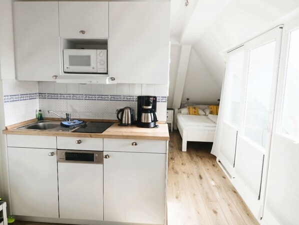 A compact kitchen with a microwave, coffee maker, and sink.