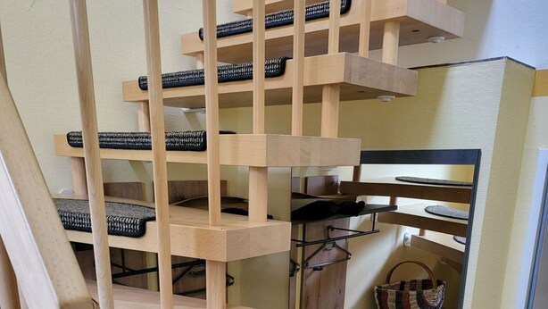 Eine Holztreppe im Schneckenform mit mehreren Ebenen, jede mit einer gewobenen Sitzgelegenheit.