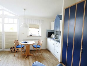 A compact kitchen with white cabinets, a blue door, and a round table with chairs.