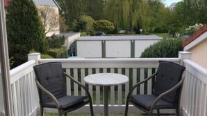 Eine Holzterrasse mit zwei dunkelgrauen Stühlen und einem kleinen runden Tisch.