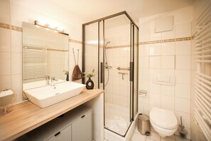 Une salle de bain moderne avec une douche à parois de verre, un lavabo blanc et des toilettes.