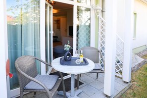 An outdoor seating area with wicker chairs and a table, a bottle of Castiza wine, and a glass.