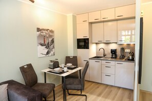 A compact kitchen with a dining area, equipped with a toaster, a coffee maker, and a kettle.