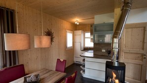 A cozy cabin interior with a dining area, a kitchen with a stove, and a large window. - Attractive Chalet on the Slopes (Sankt Georgen am Kreischberg)