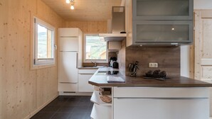 A modern kitchen with wooden walls, a large window, and a built-in TV. - Attractive Chalet on the Slopes (Sankt Georgen am Kreischberg)