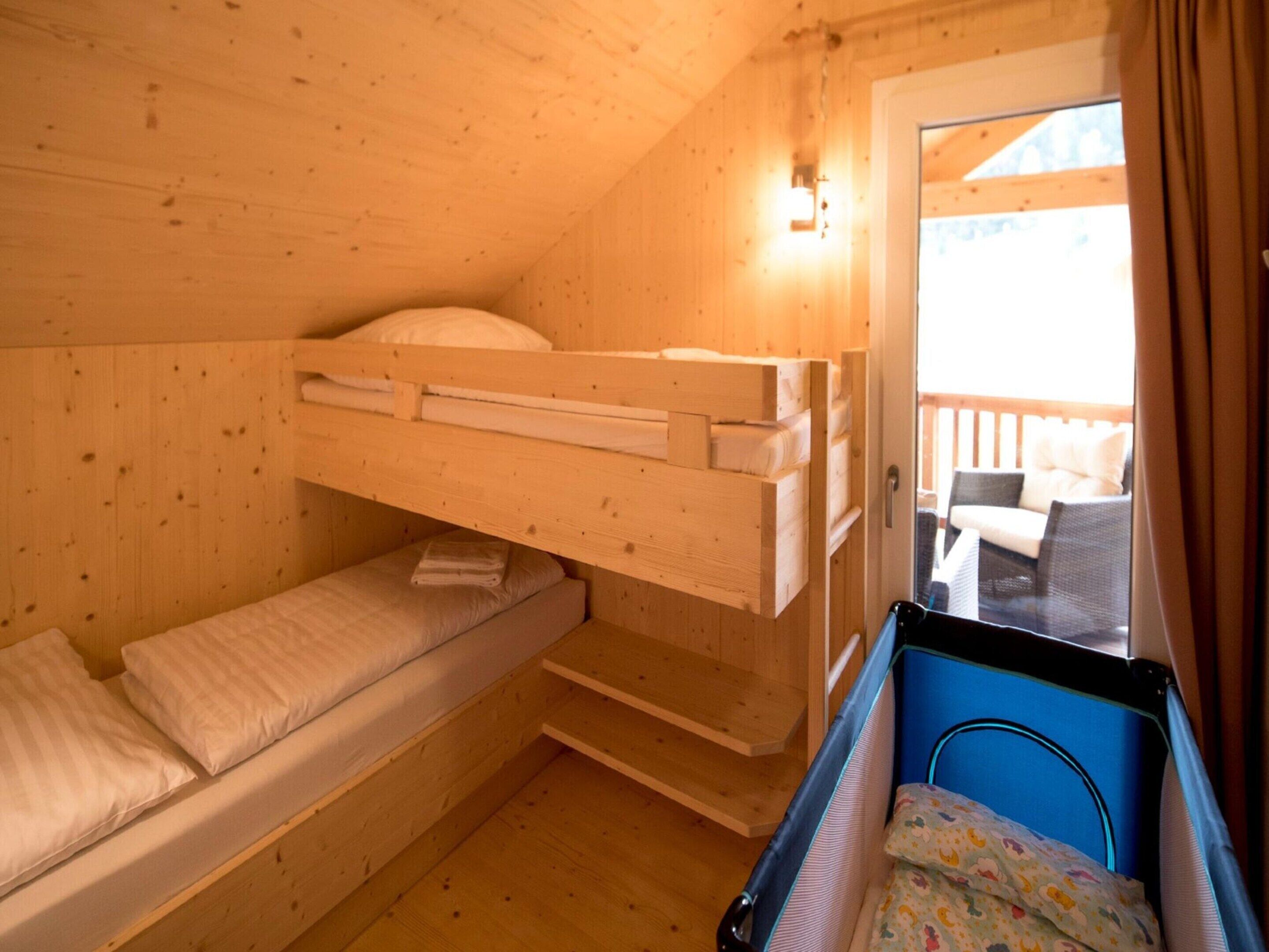 Una habitación tipo cabaña de madera con literas, una mesita y vistas a una terraza exterior.
