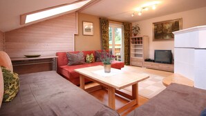 A cozy living room with a red sofa, a wooden coffee table, and a television. - Huge Holiday Home in Hopfgarten im Brixental near Ski Lift (Hopfgarten im Brixental)