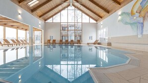 An indoor swimming pool with wooden beams, large windows, and lounge chairs. - Spacious Chalet near Ski Area in Sankt Georgen ob Murau (Sankt Georgen am Kreischberg)