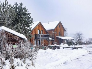 A wooden cabin with a balcony, surrounded by snow-covered trees and bushes. - Spacious Chalet near Ski Area in Sankt Georgen ob Murau (Sankt Georgen am Kreischberg)