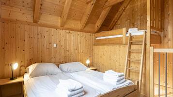 Ein Holzhütten-Zimmer mit einem Bett, zwei Nachttischen, einer Leiter und einem kleinen Fenster.