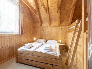 A wooden cabin bedroom with a bed, two bedside tables, a ladder, and a window with curtains. - Splendid Holiday Home in Kreischberg Murau near Ski Resort (Sankt Georgen am Kreischberg)