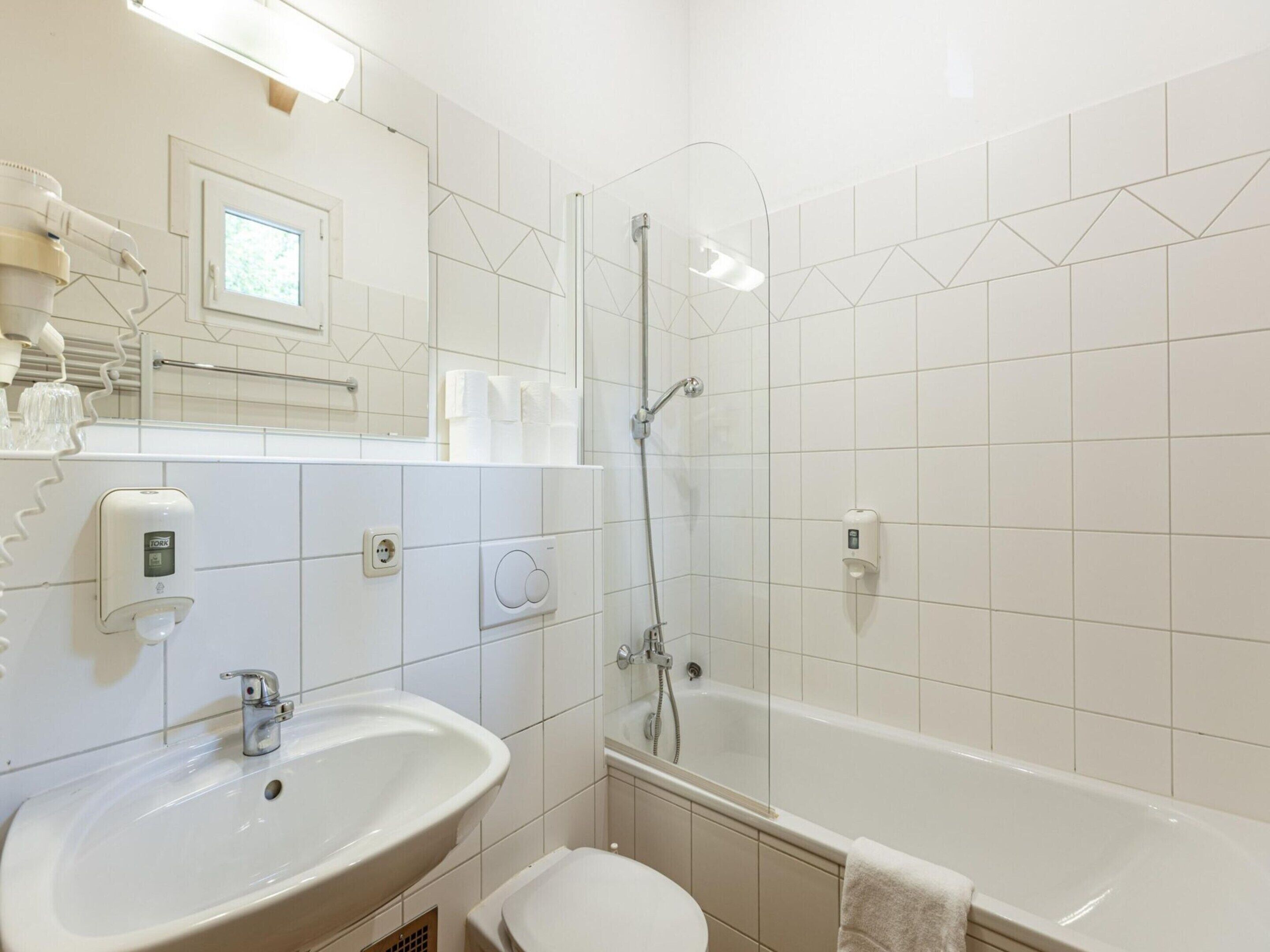 A modern bathroom with a sink, toilet, and shower.