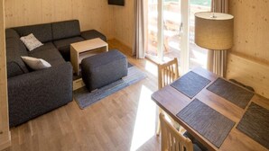 A cozy room with a sofa, a small table, and a lamp. - Snug Chalet With Sauna (Sankt Georgen am Kreischberg)