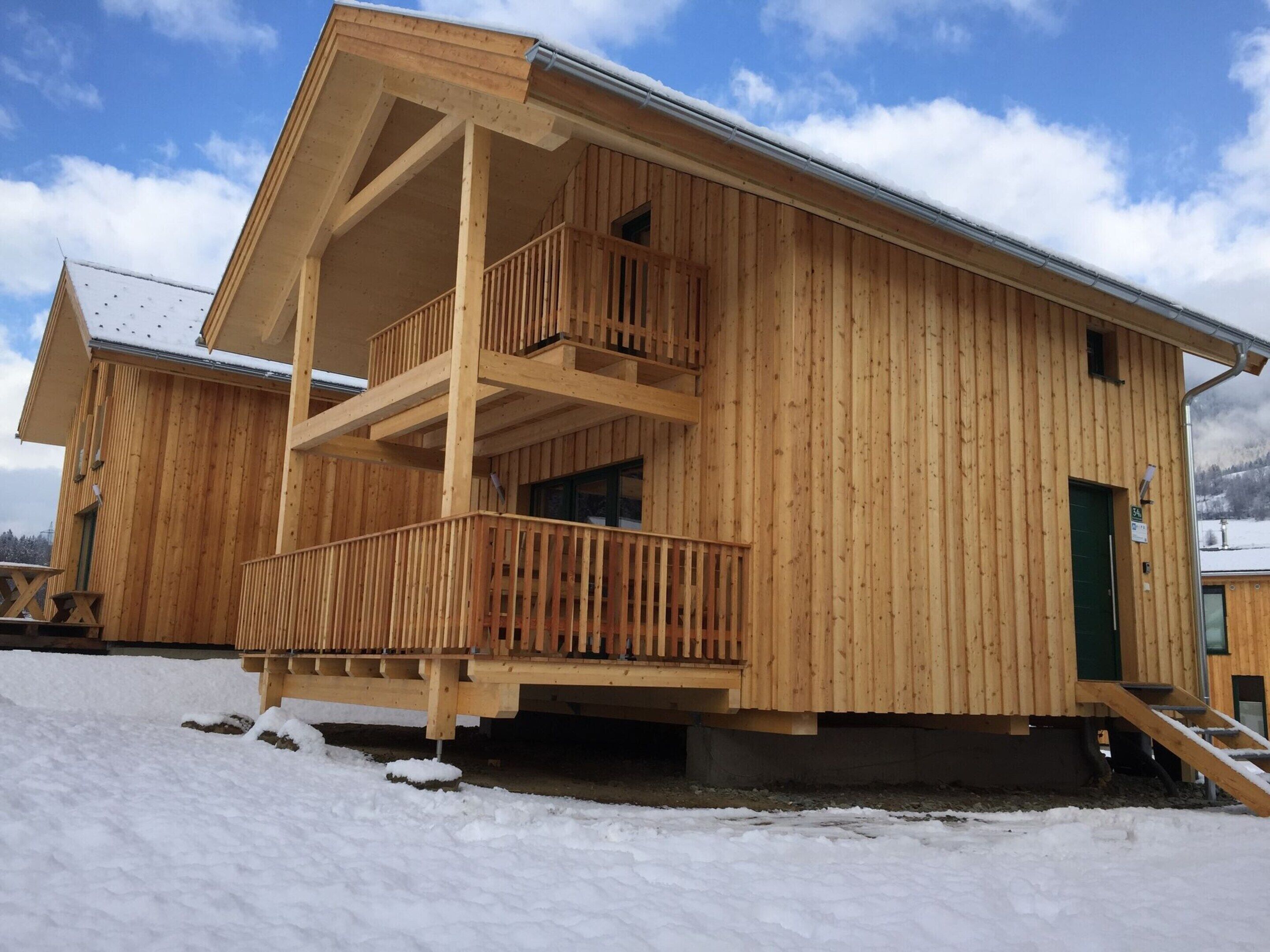 A wooden cabin with a balcony, a green door, and a number 34 sign.