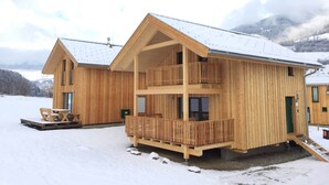 A wooden cabin with a balcony and a covered outdoor seating area. - Snug Chalet With Sauna (Sankt Georgen am Kreischberg)