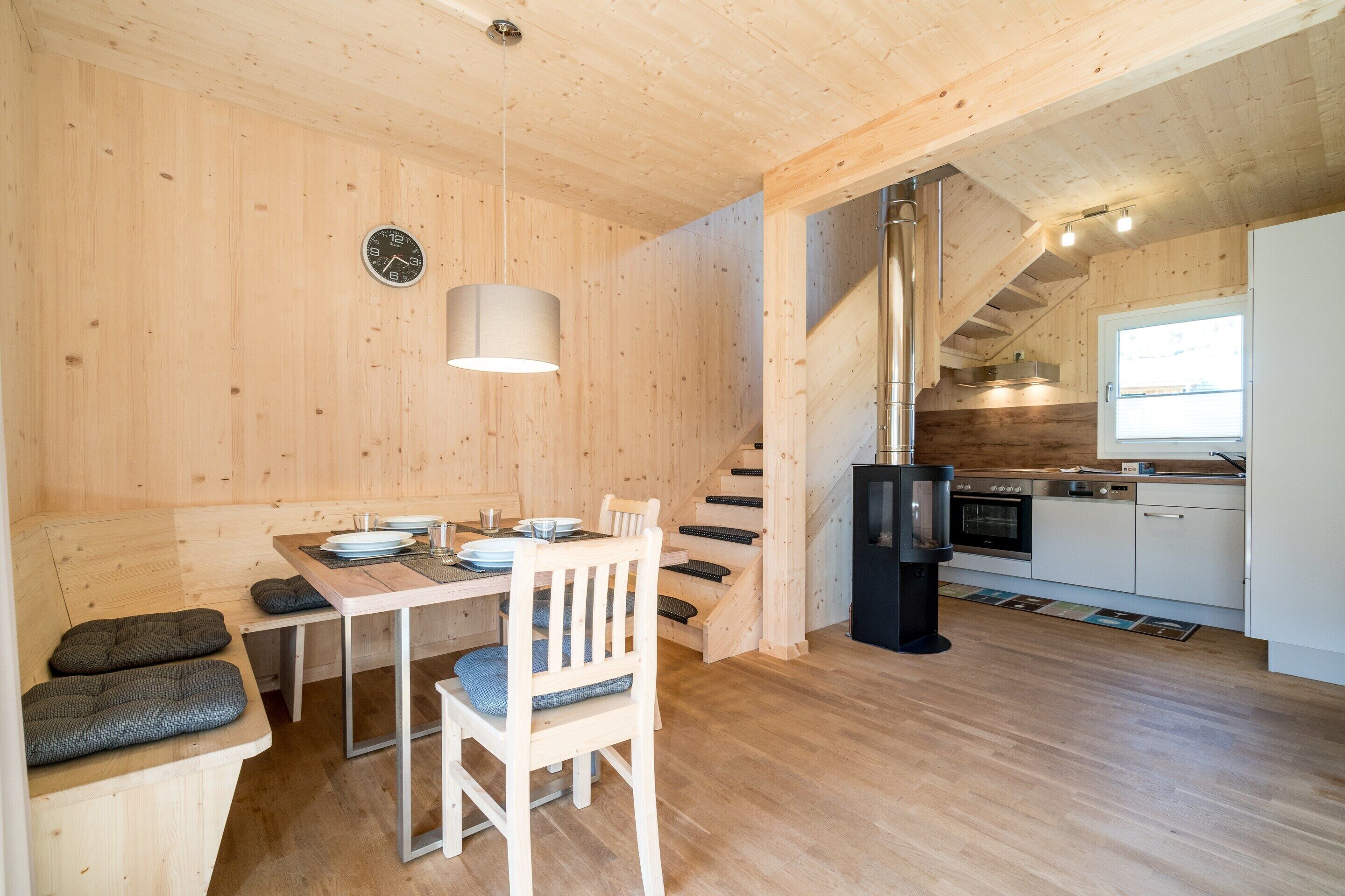 A wooden interior with a dining area, a kitchen, and a staircase.