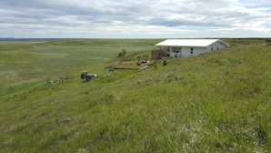 A white house with a large porch on a grassy hill. - Beindalsholt (Rangárþing ytra)