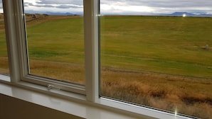 A view from a window overlooking a grassy field with mountains in the distance. - Beindalsholt (Rangárþing ytra)
