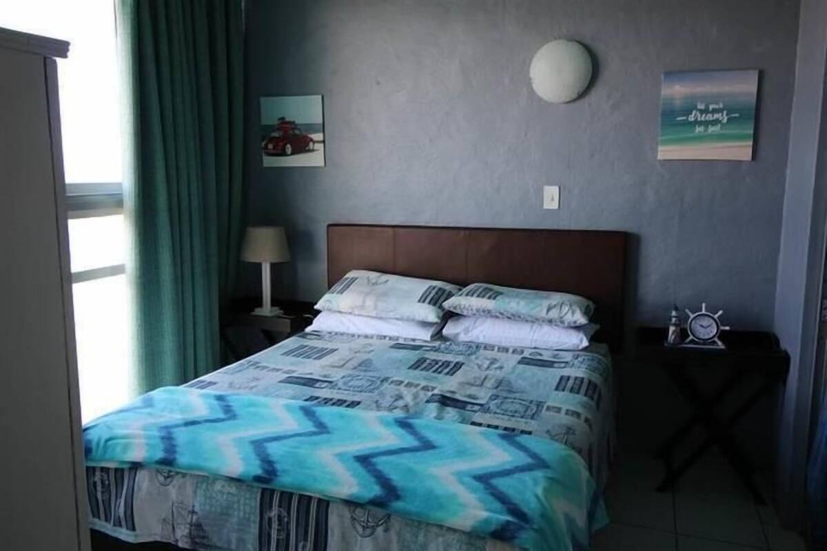 Une chambre à coucher comprenant un lit, une table de chevet, une horloge et deux éléments de décoration murale.