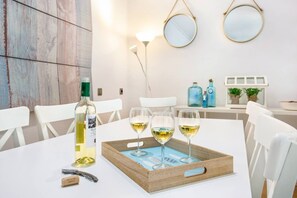 A dining table with a bottle of white wine, three wine glasses, and a wooden tray. - Stay U-nique Apartment Provença (Barcelona)