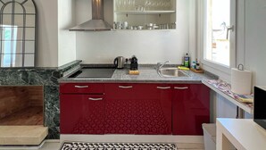 A modern kitchen with a stainless steel range hood, a granite countertop, a built-in sink, and red patterned cabinets. - Stay U-nique Apartment Sèneca (Barcelona)