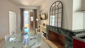 A modern living room with a glass dining table, white chairs, a fireplace, and a large arched window. - Stay U-nique Apartment S èneca (Barcelona)