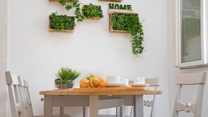 A dining area with a wooden table, chairs, and a wall-mounted plant display. - Stay U-nique Apartment Sicília (Barcelona)