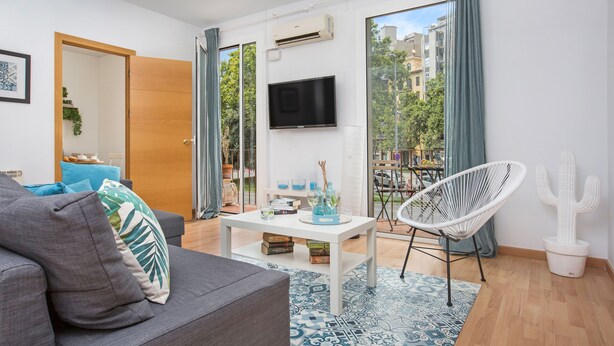 A modern living room with a grey sofa, a white coffee table, a white chair, and a cactus decoration. - Stay U-nique Apartment Sicília (Barcelona)