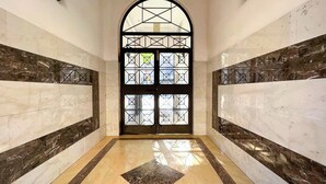 A hallway with a polished marble floor, a large arched door with a geometric pattern, and walls with a marble finish. - Stay U-nique Apartment Sicília (Barcelona)