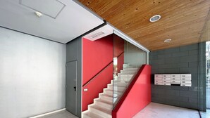 Un interior moderno con una escalera, barandilla de cristal y buzón empotrado en la pared.