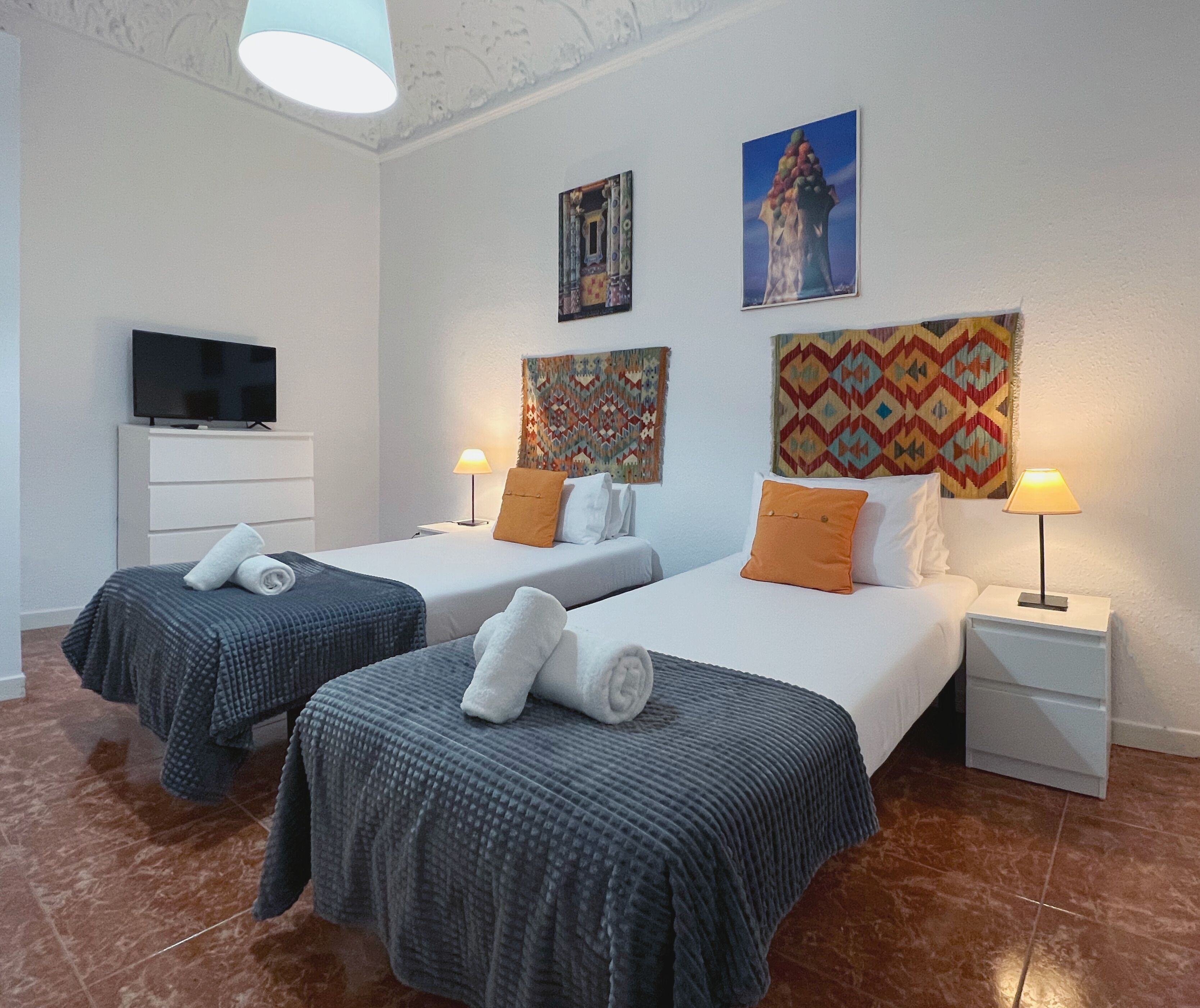 A hotel room with two beds, a TV, and artwork on the walls.