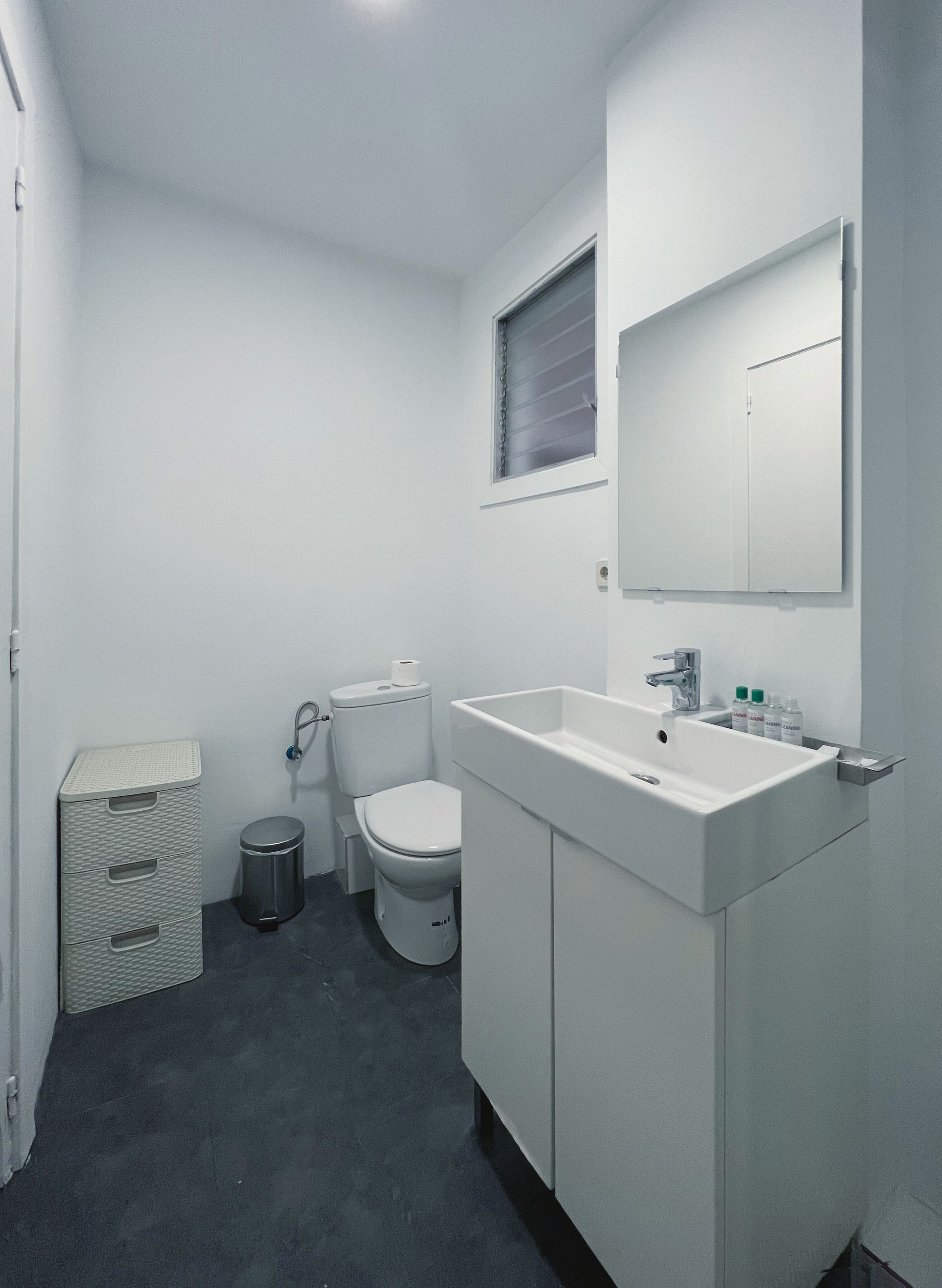 Une salle de bain moderne et compacte, comprenant des toilettes, un lavabo et un meuble de rangement.