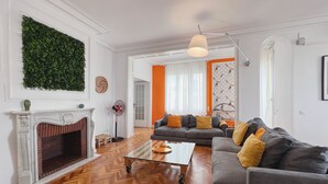 A living room with a fireplace, a sofa set, a coffee table, and a herringbone-patterned wooden floor.