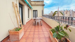 A balcony with a tiled floor, a table with chairs, and potted plants.