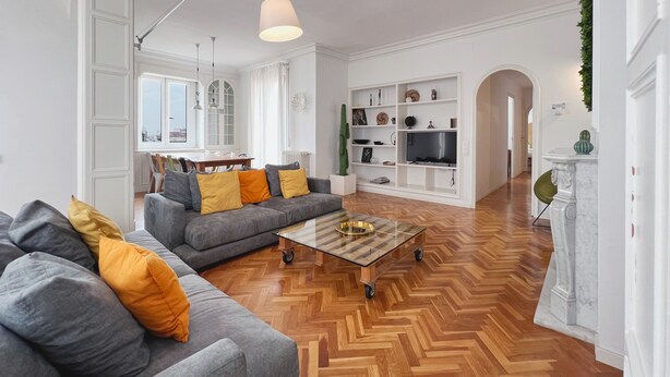 A spacious living room with a grey sofa, a coffee table, and a TV stand.