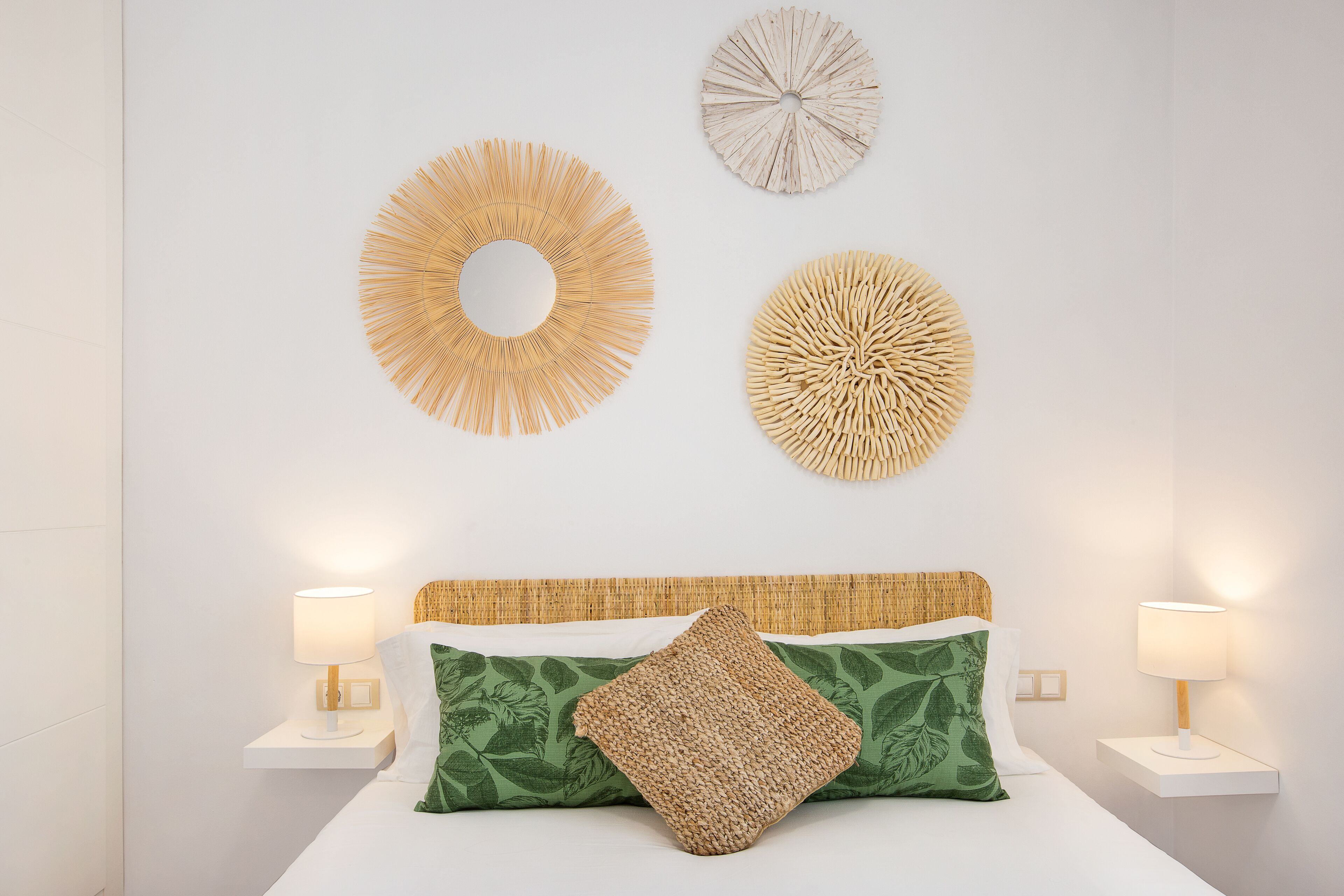 A neatly arranged bedroom with a bed, two bedside lamps, and three wall decorations.