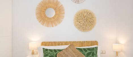 A neatly arranged bedroom with a bed, two bedside lamps, and three wall decorations.