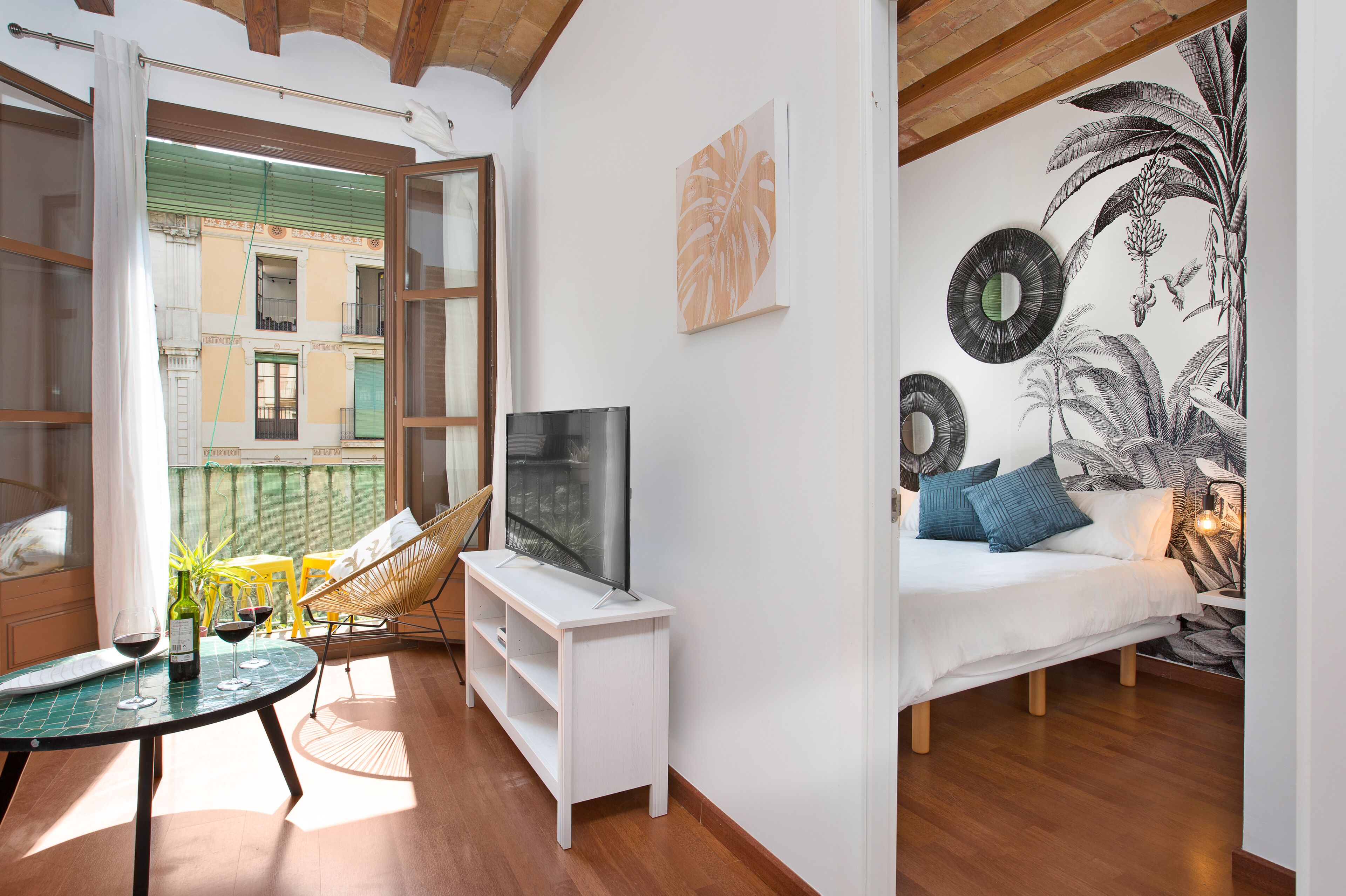 A modern living room with a TV, seating area, and a balcony with a view.