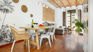 A dining area with a wooden table, wicker chairs, and a modern chandelier. - Stay U-nique Apartments Girona (Barcelona)