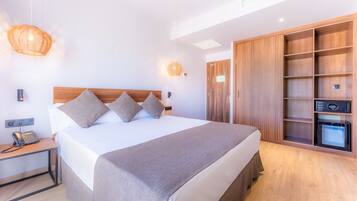 Una habitación de hotel moderna con una cama grande, mesitas de noche, un armario y una minibar.
