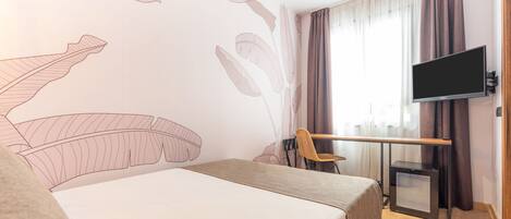Une chambre d’hôtel équipée d’un lit, d’un bureau, d’une chaise, d’une télévision et d’un petit radiateur.