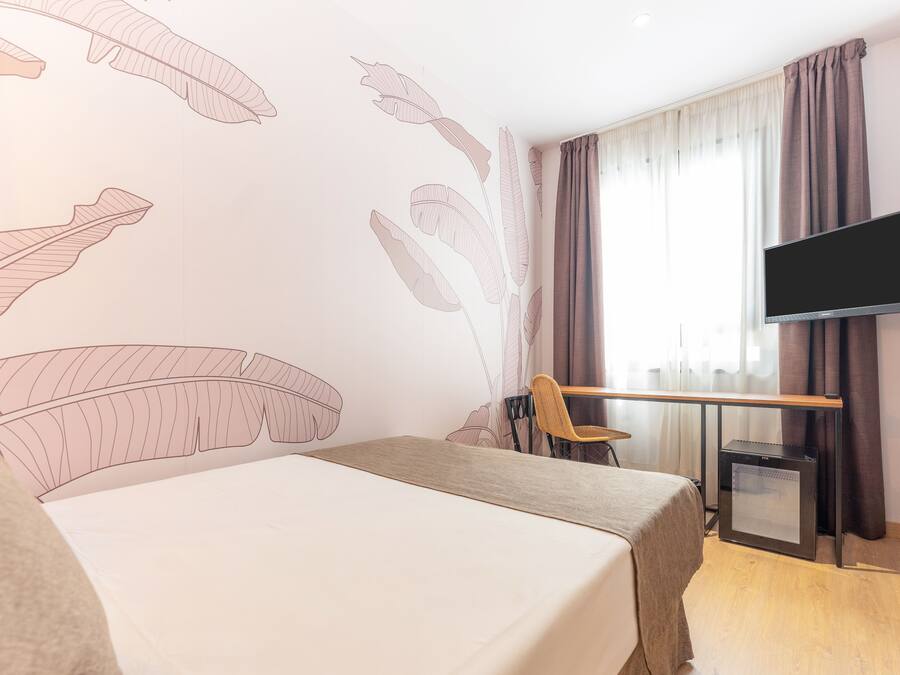 Habitación de hotel con cama, escritorio, silla, televisor y un pequeño calentador.